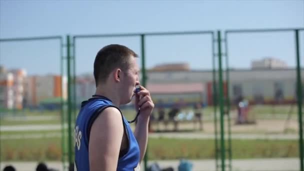 Bobruisk, Belarus - 12 August 2019: Close side view of referee blowing whistle and making hand signal on outdoor court - Séquence, vidéo