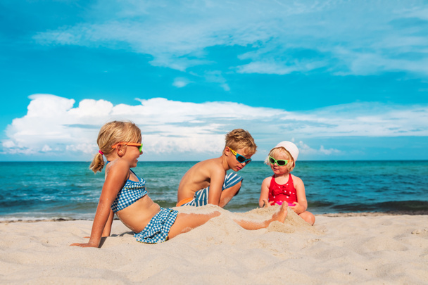 kids- boy and girls- play with sand on beach - Photo, Image