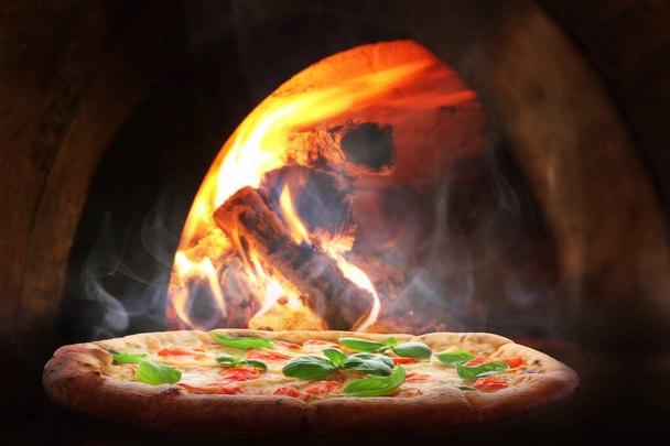 Hot pizza baking in firewood oven - Photo, Image