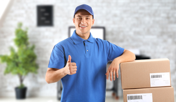 Delivery man with boxes showing thumb-up in office - Fotografie, Obrázek