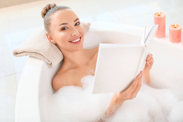 Beautiful young woman reading book in bathtub - Foto, Imagem