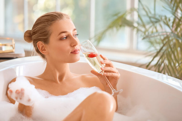 Mulher bonita bebendo champanhe no banheiro
 - Foto, Imagem