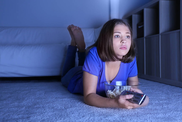 Tiener meisje met popcorn kijken TV thuis laat in de avond - Foto, afbeelding