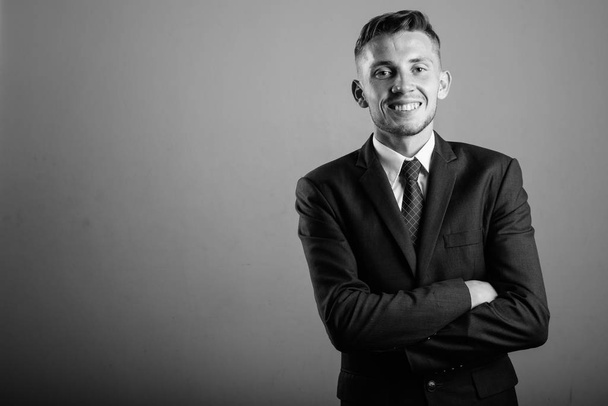 Studio shot of young businessman in suit against gray background in black and white - Photo, image