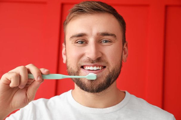 Handsome man with tooth brush on color background - Fotoğraf, Görsel