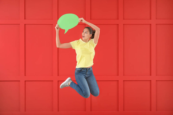 Jumping young woman with speech bubble against color background - Photo, Image