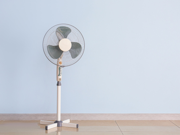Современный электрический вентилятор возле цветной стены
 - Фото, изображение