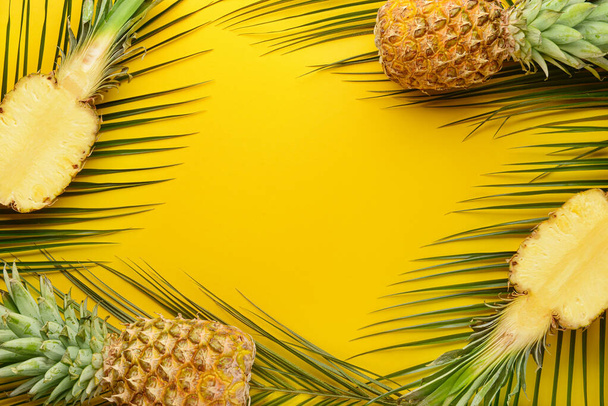 Fresh ripe pineapples and tropical leaves on color background - Фото, зображення
