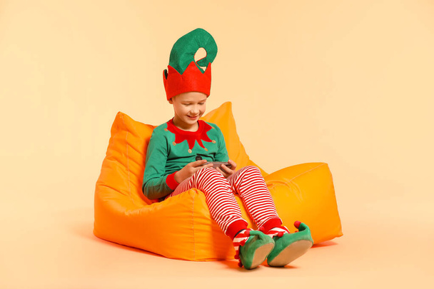 Little boy in costume and with mobile phone on color background - Фото, изображение