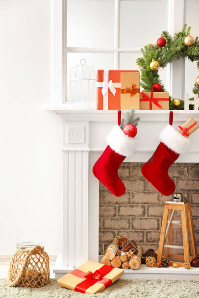 Skarpetki świąteczne z prezentami wiszące na kominku w pokoju - Zdjęcie, obraz