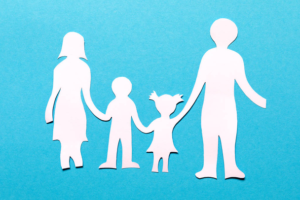 Family paper chain cutout holding hands on the blue background - Foto, imagen