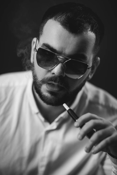 man in sunglasses and white shirt smoking - Foto, afbeelding