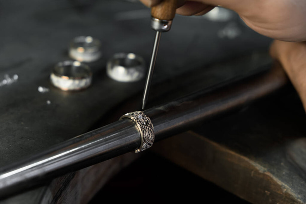  Close-up of hand of a goldsmith setting the diamond on the ring. Craft jewelery making with professional tools.  - Fotó, kép