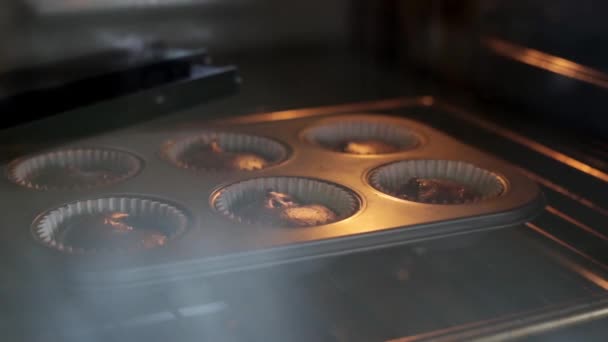 közeli kilátás sütés tál csokoládé cupcakes idő kiesés a növekvő tészta muffinok sütőtálcán - Felvétel, videó