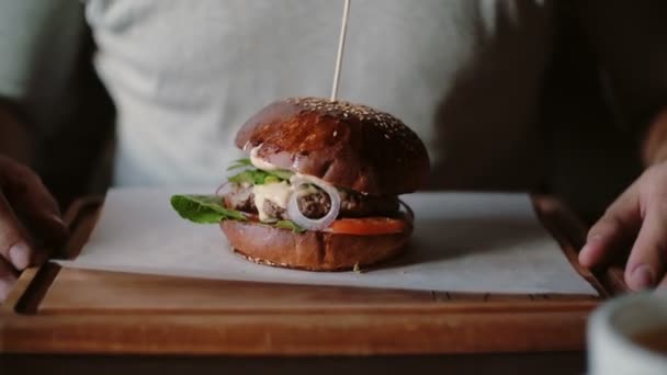 νόστιμο burger είναι μεγάλη σε ένα ξύλινο δίσκο ένας άνθρωπος παίρνει τα χέρια του και επρόκειτο να φάει - Πλάνα, βίντεο