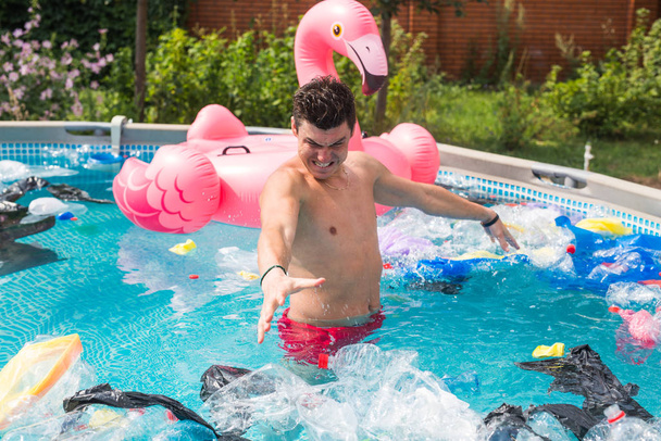 Ökologie, Plastikmüll, Umweltnotstand und Wasserverschmutzung - geschockter Mann steht in schmutzigem Schwimmbad - Foto, Bild