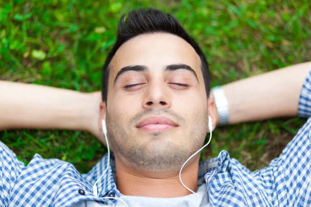 Man listening to music on the grass - Zdjęcie, obraz