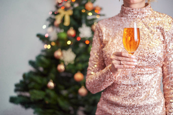Donna che tiene un bicchiere di champagne con albero di Natale sullo sfondo
 - Foto, immagini