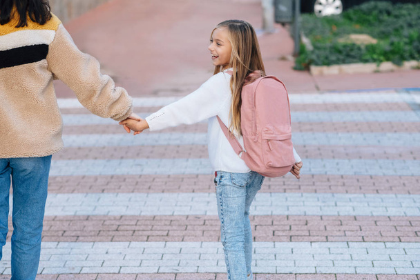 Маленькая девочка по дороге в школу с матерью и розовым рюкзаком
 - Фото, изображение