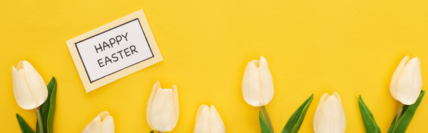 top view of tulips, greeting card with happy Easter lettering on yellow colorful background, panoramic shot - Photo, Image