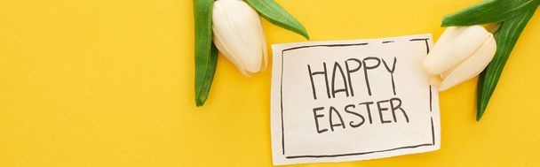 top view of greeting card with happy Easter lettering and tulips on yellow colorful background, panoramic shot - Fotoğraf, Görsel