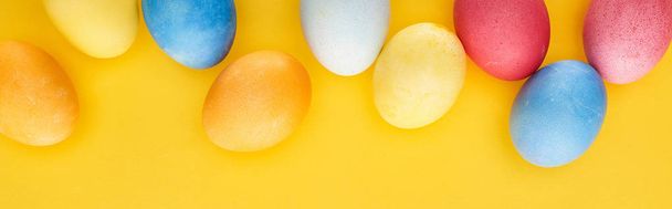 top view of multicolored painted Easter eggs on yellow background, panoramic shot - Photo, Image