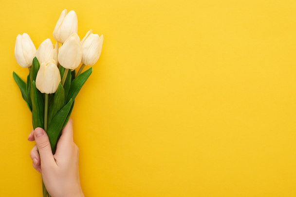vista cortada de mulher segurando tulipas primavera no fundo amarelo colorido
 - Foto, Imagem