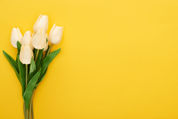 Верхний вид весенних тюльпанов на красочном желтом фоне - Фото, изображение