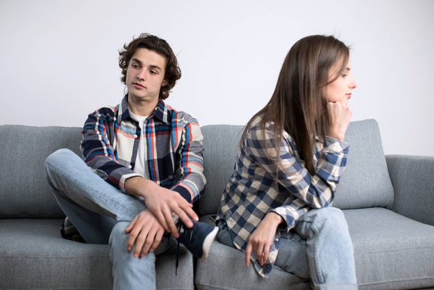 Ofendida joven hombre y mujer sentado en el sofá
 - Foto, Imagen