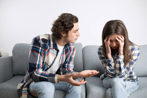 Casal jovem enfrenta crise no relacionamento e conversando na sala de estar
 - Foto, Imagem