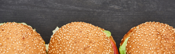 vista superior de deliciosas hamburguesas frescas con queso sobre mesa negra, plano panorámico
 - Foto, Imagen