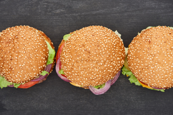top view of delicious fresh cheeseburgers on black table - 写真・画像