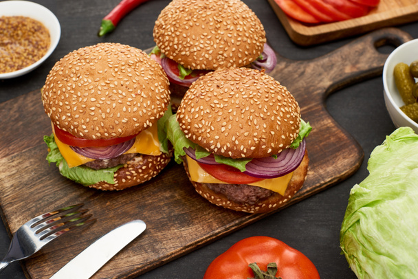 tasty fresh cheeseburgers on wooden board with cutlery - Photo, Image