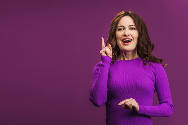 smiling woman showing idea gesture on purple background - Foto, afbeelding