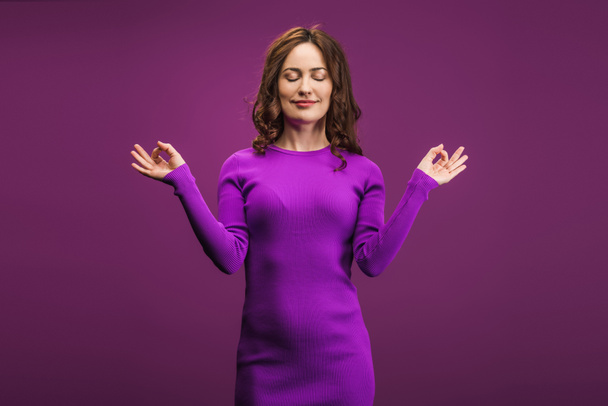 positive woman meditating with closed eyes on purple background - Фото, изображение