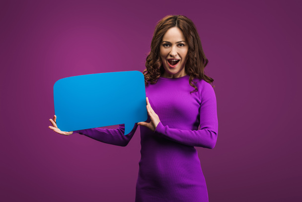 збуджена жінка тримає мовну бульбашку на фіолетовому фоні
 - Фото, зображення