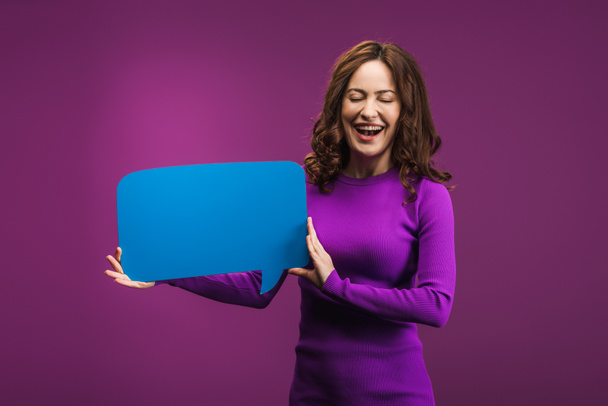 laughing woman holding speech bubble on purple background - Foto, immagini