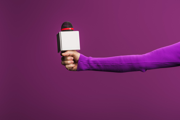 oříznutý pohled reportéra držícího mikrofon na fialovém pozadí - Fotografie, Obrázek