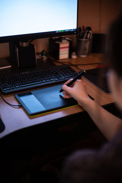 Uma mulher usando tablet gráfico com caneta e trabalhando em sua mesa
 - Foto, Imagem