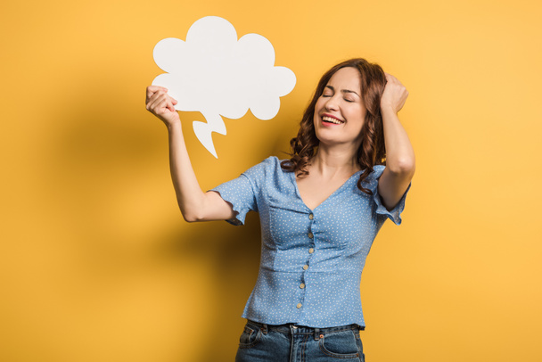 excited girl laughing while holding thought bubble on yellow background - Photo, Image