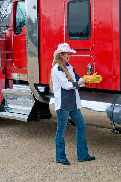 女性トラックの運転手は彼女の手袋に大きなリグを検査する - 写真・画像