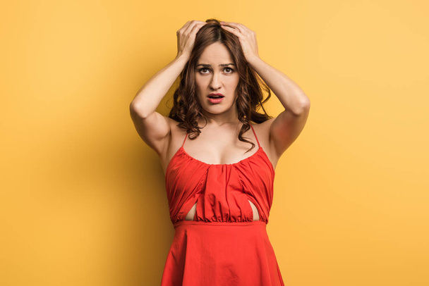 displeased young woman holding hands on head on yellow background - Foto, immagini