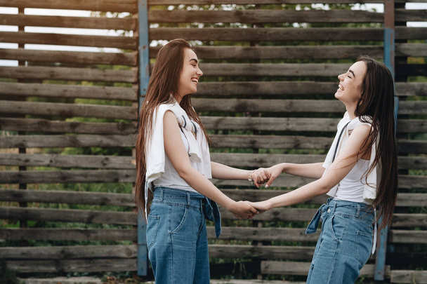 Portret van twee jonge Brunette tweeling zusters gekleed als in jeans en wit T-shirt, beste vrienden voor altijd concept - Foto, afbeelding