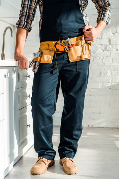 cropped view of installer with tool belt standing with clenched fist  - Fotografie, Obrázek