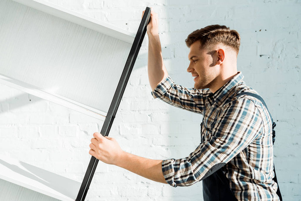 side view of handsome installer holding rack near brick wall  - Photo, Image