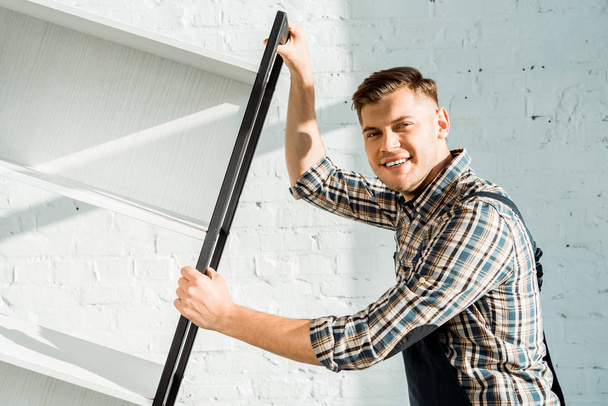 veselý instalátor drží stojan u cihlové zdi  - Fotografie, Obrázek