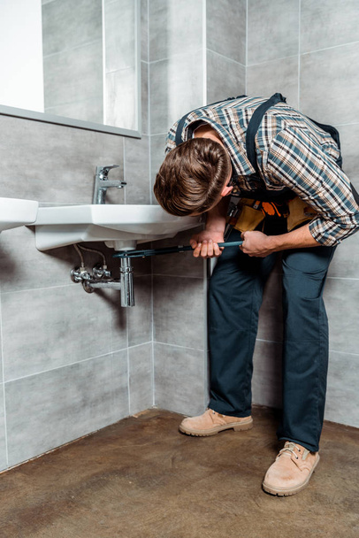 instalátor drží klouby kleště v blízkosti potrubí v koupelně  - Fotografie, Obrázek
