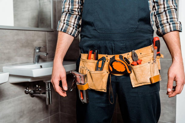 cropped view of installer with tool belt standing in bathroom  - Фото, зображення