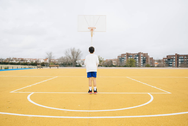 若いです男の子遊びます上の黄色バスケットボールコート屋外. - 写真・画像