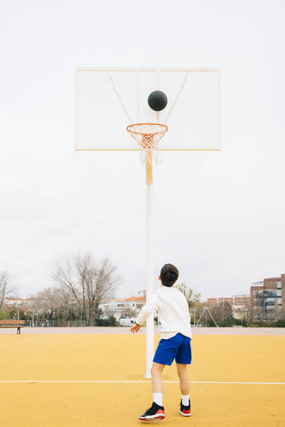 Jeune garçon jouant sur le terrain de basket jaune extérieur
. - Photo, image